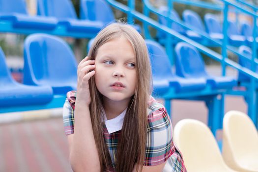 pretty girl in school dress uniform on the blue and yellow tribune of the school stadium. school time. tween