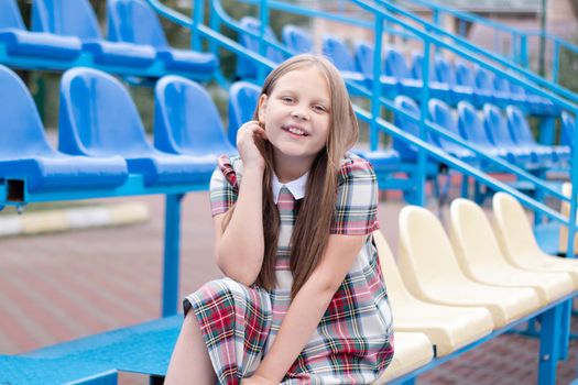 Stadium tribune. tweet brunette girl in dress near Tribunes and plastic colorful chairs in the sports stadium