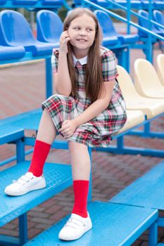 Stadium tribune. tweet brunette girl in dress near Tribunes and plastic colorful chairs in the sports stadium