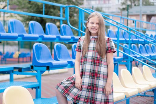 Stadium tribune. tweet brunette girl in dress near Tribunes and plastic colorful chairs in the sports stadium