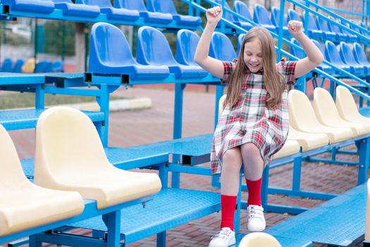 Stadium tribune. tweet brunette girl in dress near Tribunes and plastic colorful chairs in the sports stadium