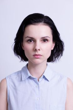 woman in a blue sleeveless office shirt, light background. High quality photo