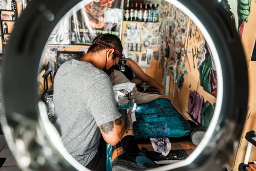 Latino tattoo artist working on a design seen from inside a ring of light in his studio in Managua Nicaragua