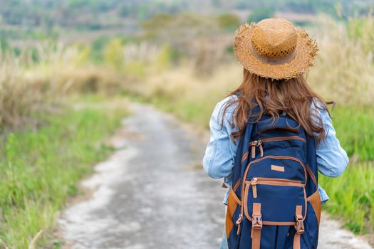 woman with backpack walking on footpath in the nature