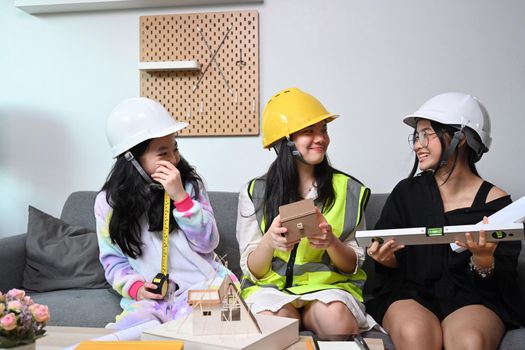 Joyful asian children in safety helmet pretend to be engineer playing together at home.