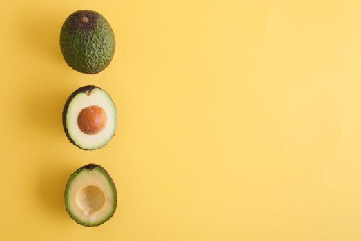 avocado whole and half on yellow background. High quality photo