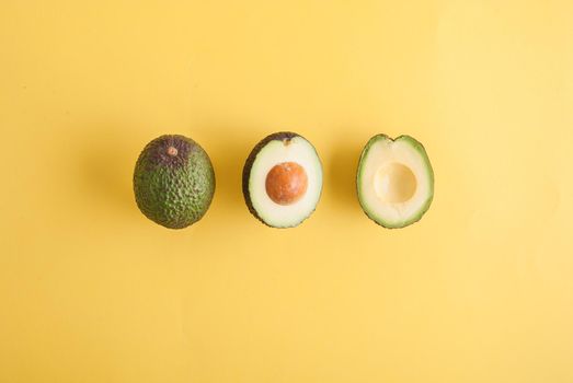 avocado whole and half on yellow background. High quality photo