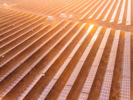 Aerial top view of a solar panels power plant. Photovoltaic solar panels at sunrise and sunset in countryside from above. Modern technology, climate care, earth saving, renewable energy concept