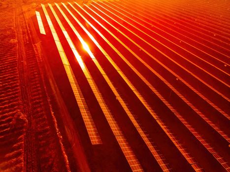 Aerial top view of a solar panels power plant. Photovoltaic solar panels at sunrise and sunset in countryside from above. Modern technology, climate care, earth saving, renewable energy concept
