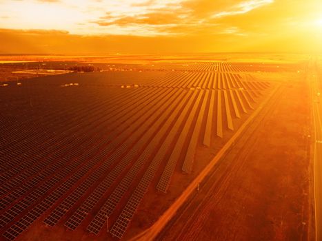 Aerial top view of a solar panels power plant. Photovoltaic solar panels at sunrise and sunset in countryside from above. Modern technology, climate care, earth saving, renewable energy concept