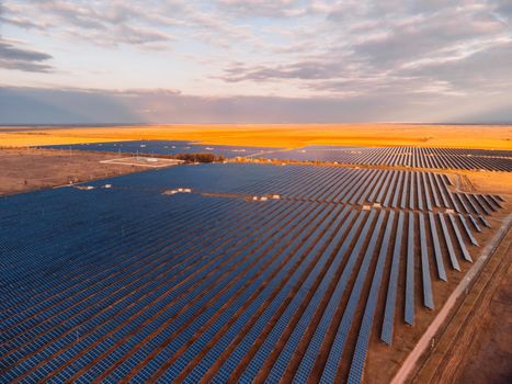 Aerial top view of a solar panels power plant. Photovoltaic solar panels at sunrise and sunset in countryside from above. Modern technology, climate care, earth saving, renewable energy concept