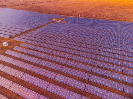 Aerial top view of a solar panels power plant. Photovoltaic solar panels at sunrise and sunset in countryside from above. Modern technology, climate care, earth saving, renewable energy concept
