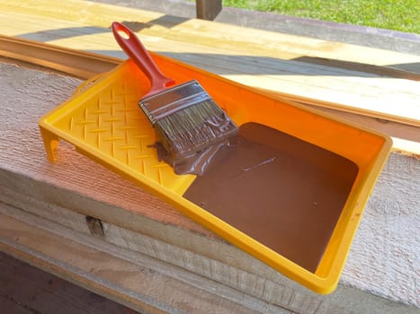 Tray of green paint with paintbrush on wooden background