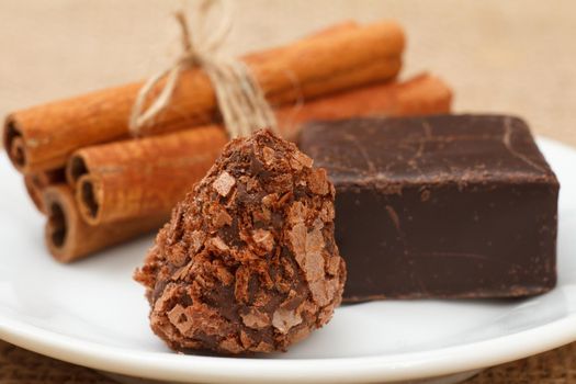 Chocolate truffle and chocolate candy on white plate with cinnamon. Selective focus on truffle