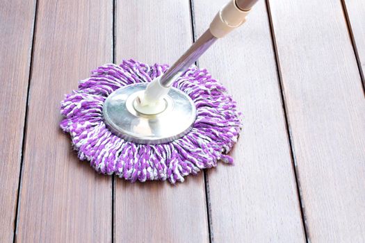 Cleaning wooden floor with purple mop top view