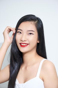 lifestyle and people concept - Beautiful happy asian girl touches her hair. Casual clothes. White background.