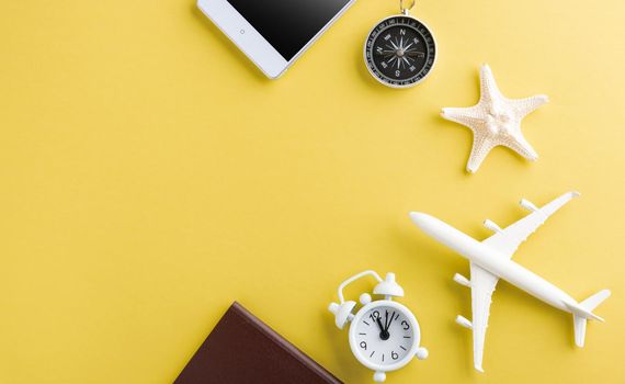 World Tourism Day, Top view of minimal model plane, airplane, starfish, alarm clock, compass and smartphone blank screen, studio shot isolated on yellow background, accessory flight holiday concept