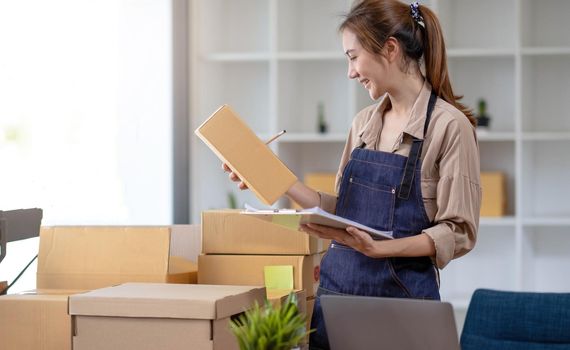 Freelance business woman smiling happy to check the stock of products that are ready to be shipped to customers according to their orders..