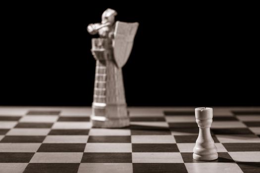 Classic white rook and the same chess piece in the form of medieval figure on the background. Selective focus on classic piece