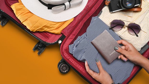 Overhead view young woman packing clothes into suitcase. Preparing for the summer vacations.