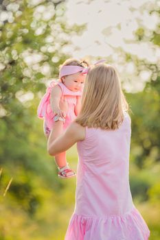 mom is circling her little daughter in a summer park