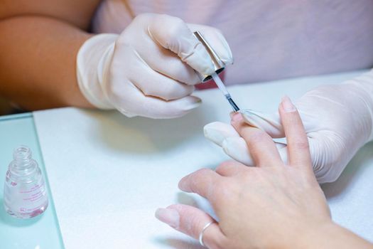 Nail beautician at work while performing the decoration and maintenance of a client's nails