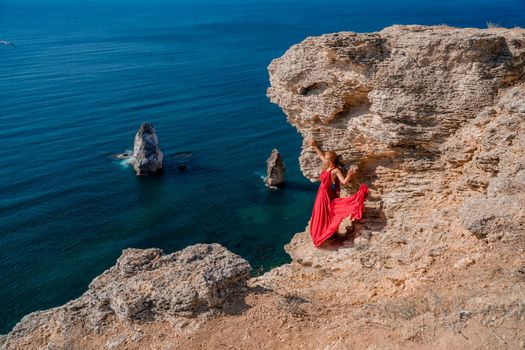 A woman in a red flying dress fluttering in the wind, against the backdrop of the sea