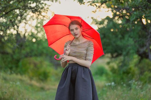 girl with a red umbrella in nature