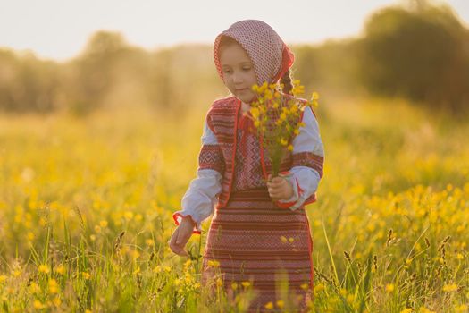 girl in national costume on the lawn with yellow flowers