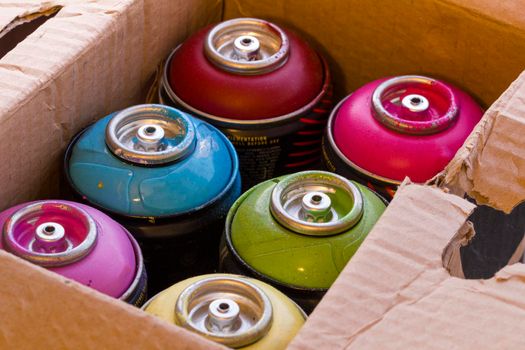 Box full of colored spray cans.