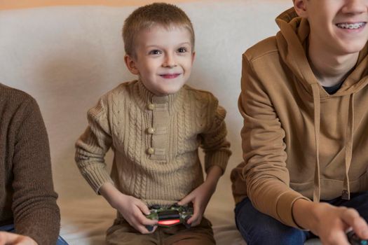 three children playing console sitting on the couch