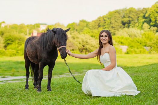 girl next to a pony on the lawn