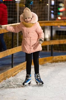 girl tries to skate on the ice rink