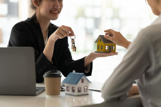 real estate agent holding house key to his client after signing contract agreement in office,concept for real estate, moving home or renting property.