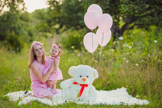 mother and daughter in pink dresses and with pink balloons in nature