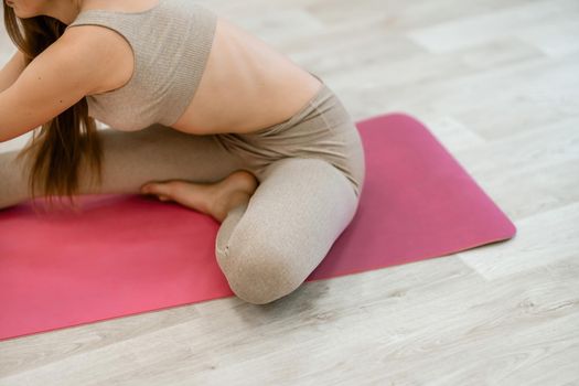 Girl does yoga. Young woman practices asanas on a beige one-ton background