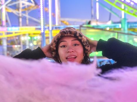 Focus on the face of a woman with a surprised expression in front of a cotton candy in a fair