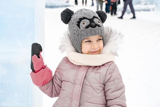 little girl in a knitted hat and scarf and ice sculptures.