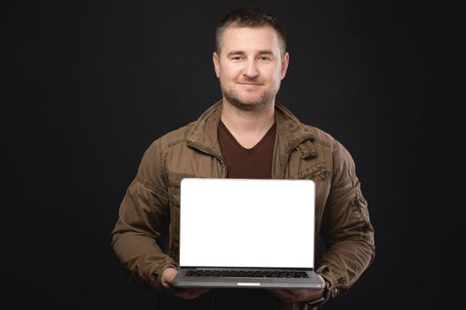 Studio portrait of a casual man holding an open laptop with a white cut-out screen in his hands. Website presentation or application copy space.