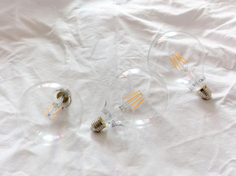 Studio photo of three light bulbs on a white rough paper surface