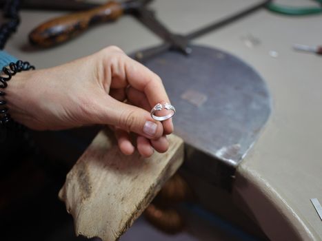 Unrecognizable adult woman holding a ring she is starting to make in her jewelry craft workshop