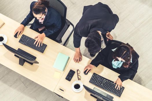 Business people wearing headset from top view in office working with computer to support remote customer or colleague. Call center, telemarketing agent service on telephone or video conference call.