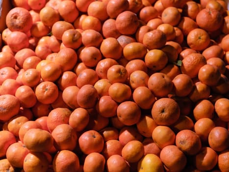 Colorful background of a pile of vivid orange mandarins in a market