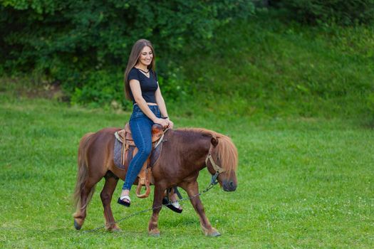 girl riding a pony on a green lawn