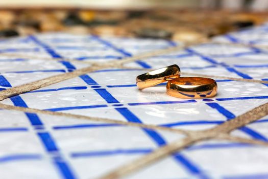 golden wedding rings over a table decorated with colored tiles