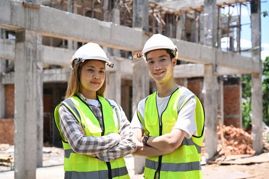 Two young architect standing with arm crossed at building construction site.