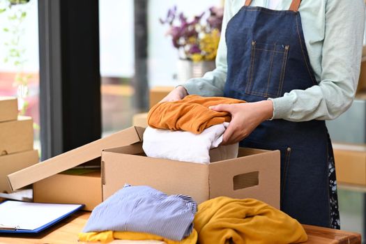 Start up business entrepreneur checking order before sending, packing product in cardboard box for delivery.