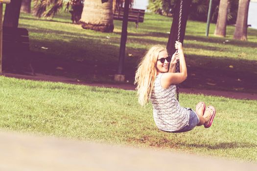 A nice fun girl in the Park, using a swing.