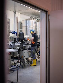 Vertical photo of a worker with protective gear working with an electronic device in a brewery