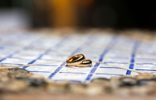 golden wedding rings over a table decorated with colored tiles